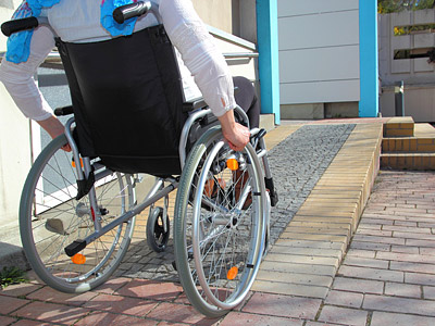 Eine Person im Rollstuhl, die eine Rampe hinauffährt.